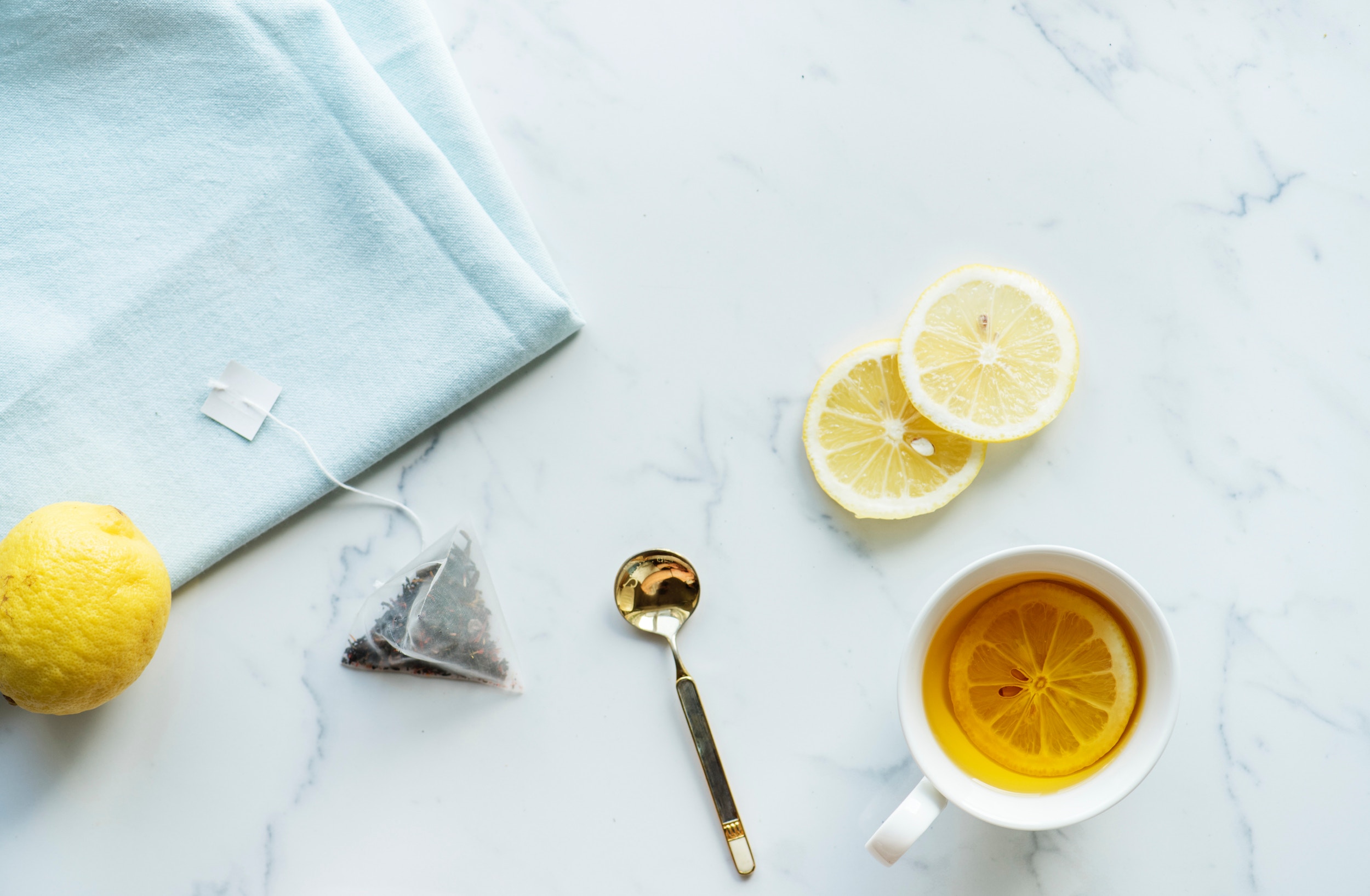 Tea bag and cup of tea on white marble worktop