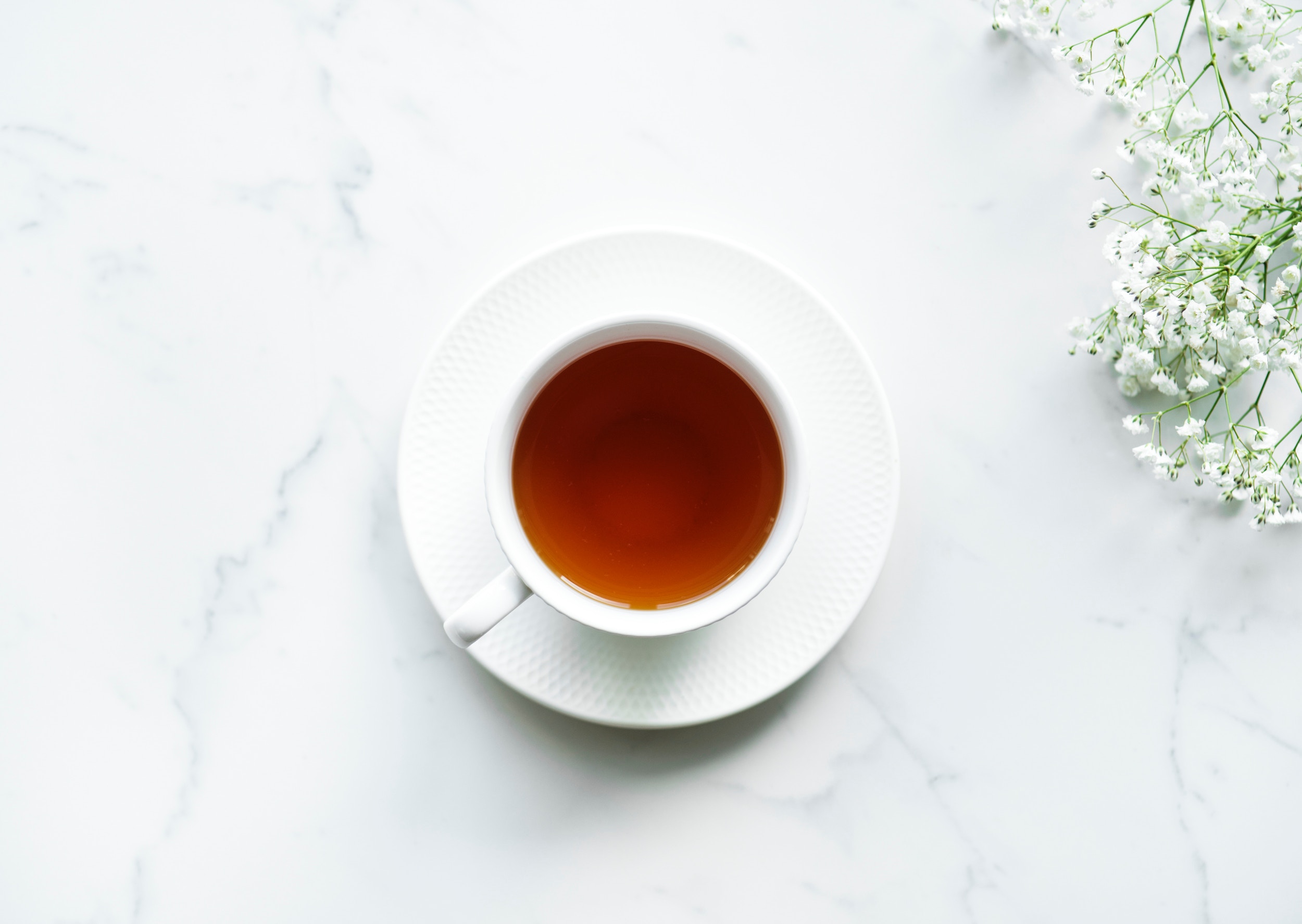 Cup of tea with saucer on white marble table